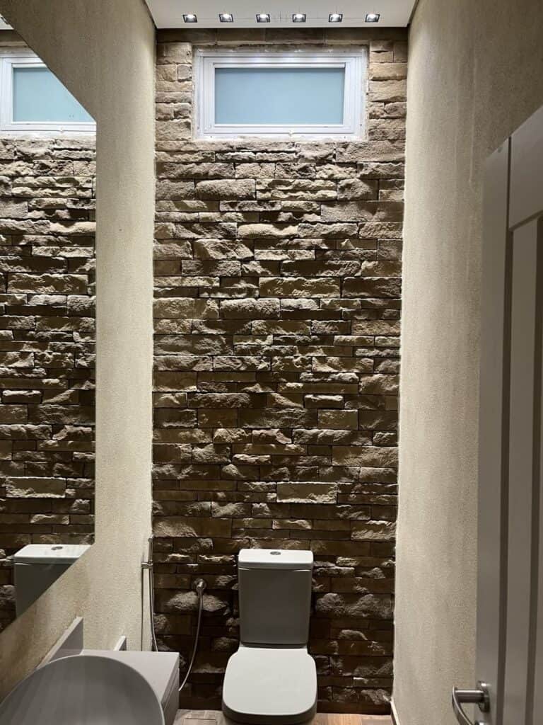 Stone wall accent wall with textured bricks in a contemporary bathroom setting.